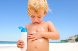 cute child applying  sunscreen  at the beach